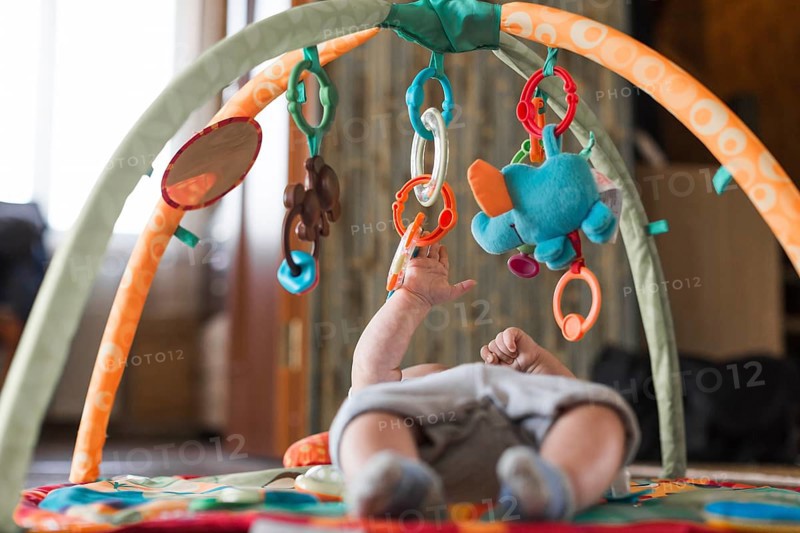 Baby lying developing rug with mobile educational toys
