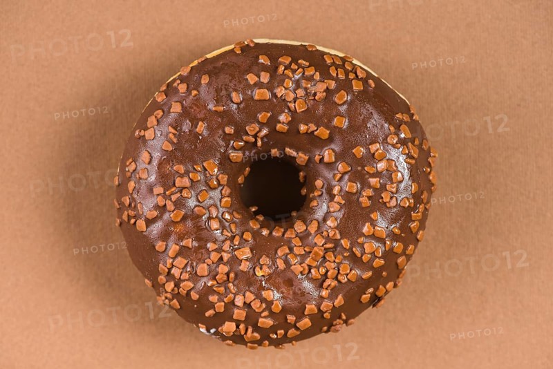 Dark chocolate doughnut with sprinkles brown background