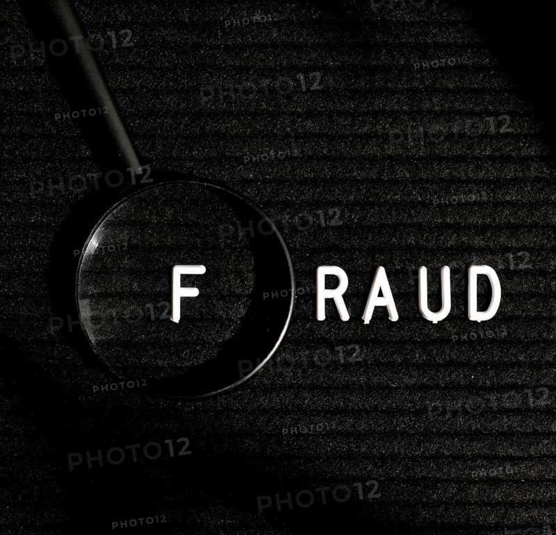Fraud word with letter magnifying glass top view