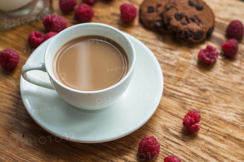 White cup coffee with chocolate cookies raspberries wooden background
