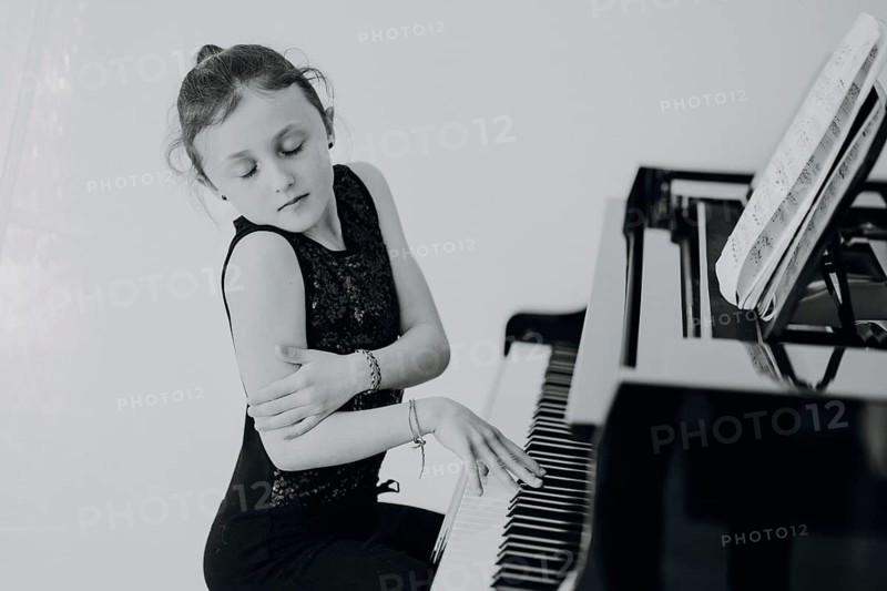 Elegant girl sits at a concert grand piano and plays the piano