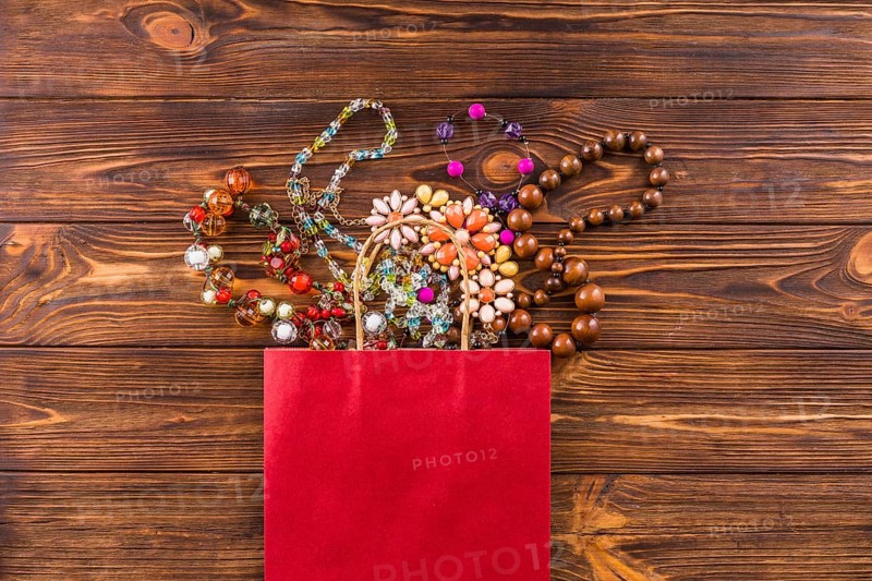 Beads jewelry red paper bag wooden background