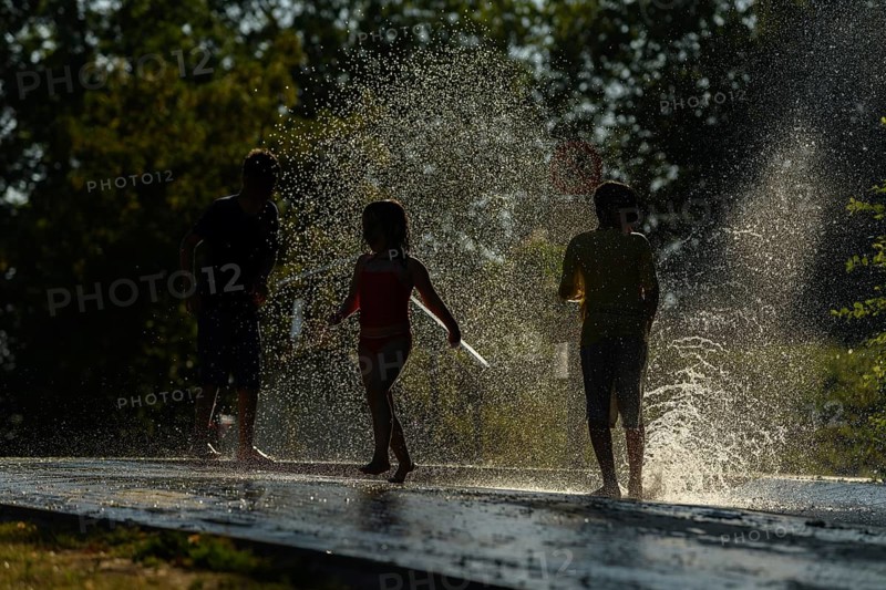 Children playing water in scorching weather in a park. Kehl