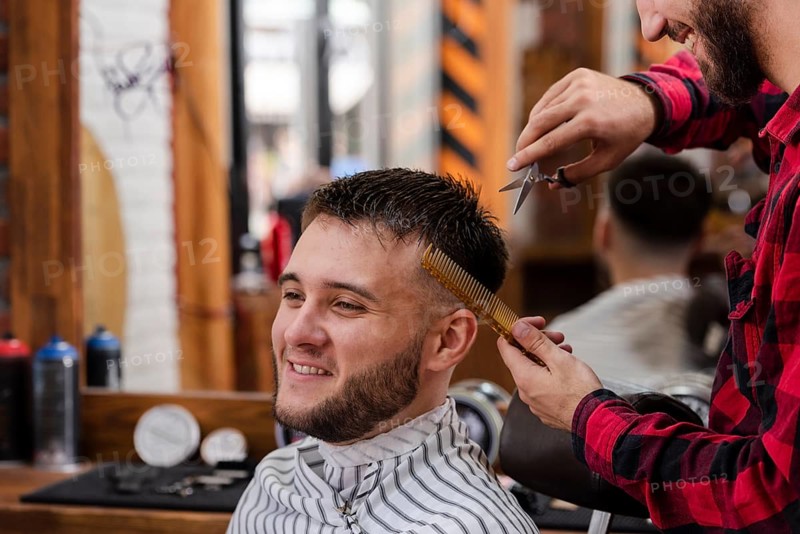 Young man trimming with scissors comb
