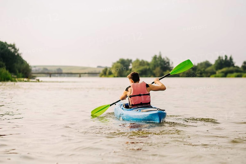 Man kayaking lake with paddle