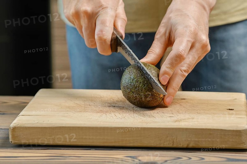 Unrecognizable man cuts avocado on half