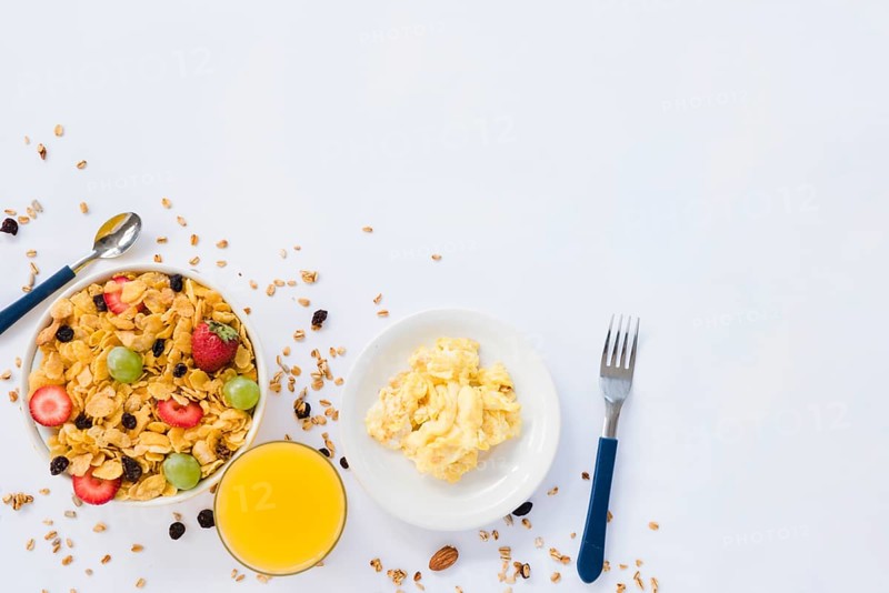 Scrambled eggs juice glass cornflakes with dried fruits white background