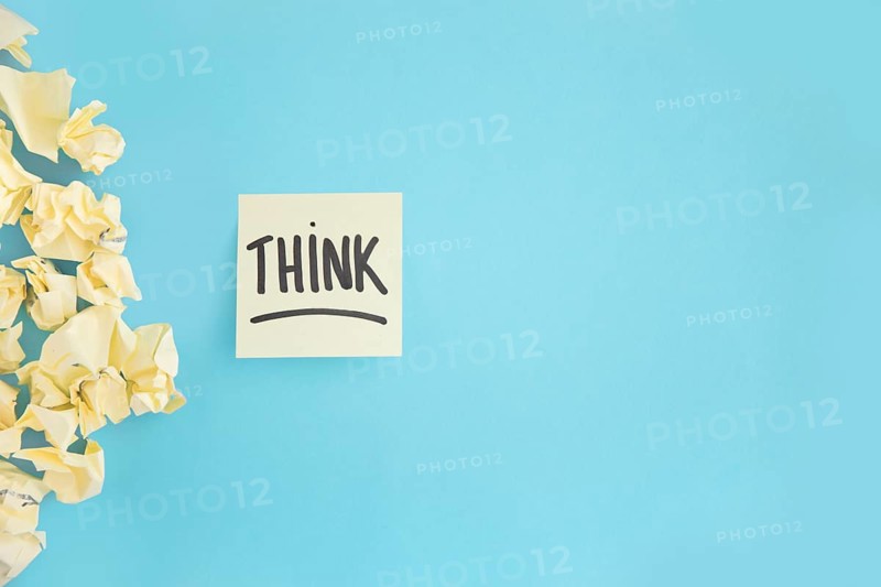 Crumpled yellow paper with think witten text adhesive note blue background