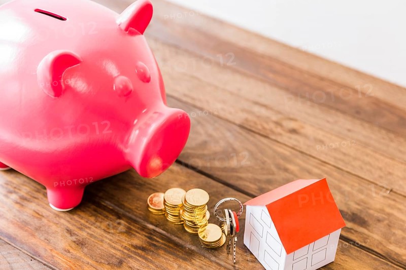 Piggybank stacked coins house key wooden desk