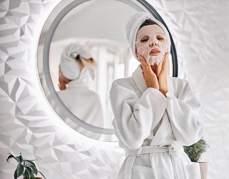 Young woman using beauty face mask