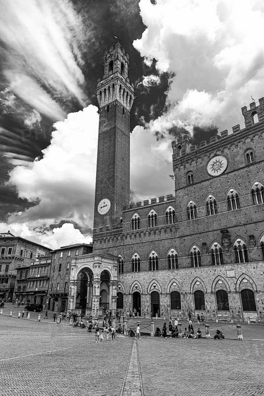 Atmospheric clouds at Piazza del Campo with its bell tower Torre del Mangia and the town hall Palazzo Pubblico