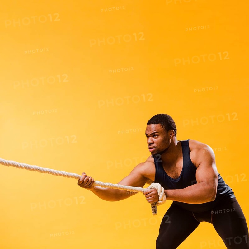 Athletic man gym outfit pulling rope with copy space