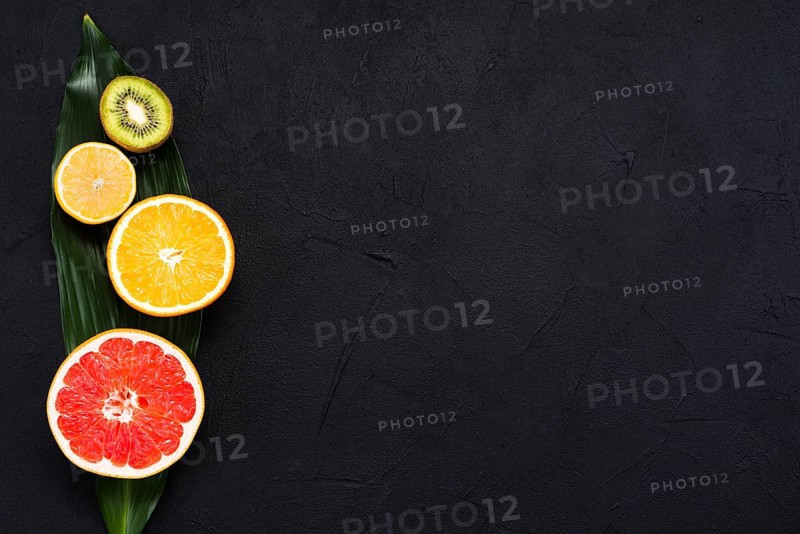 Arrangement half tropical fruits banana leaf black background