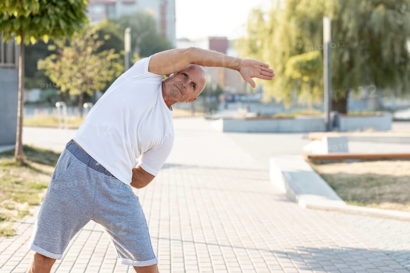Elder man stretching sidewalk
