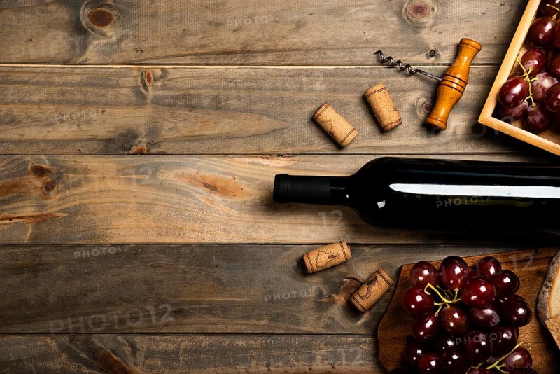 Flat lay bottle wine surrounded by corks red grapes