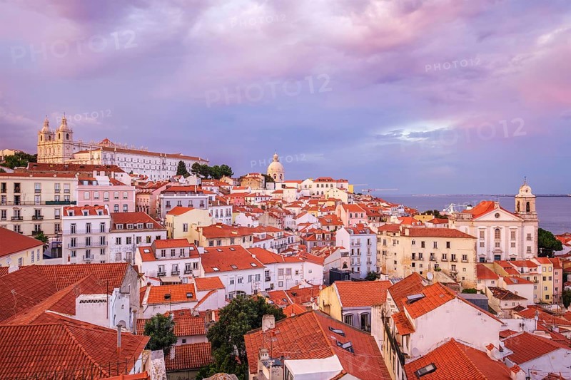 View of Lisbon famous view from Miradouro de Santa Luzia tourist viewpoint over Alfama old city district on sunset with dramatic overcast sky. Lisbon