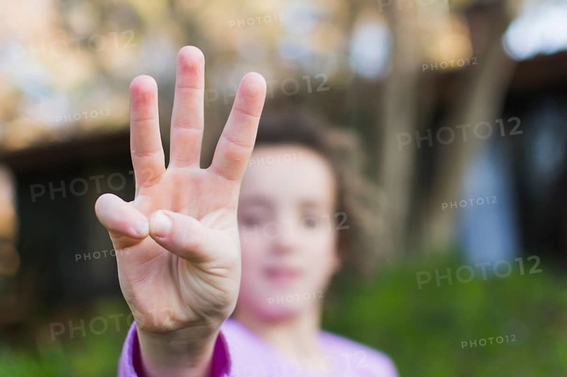 Girl showing three finger salute hand gesture