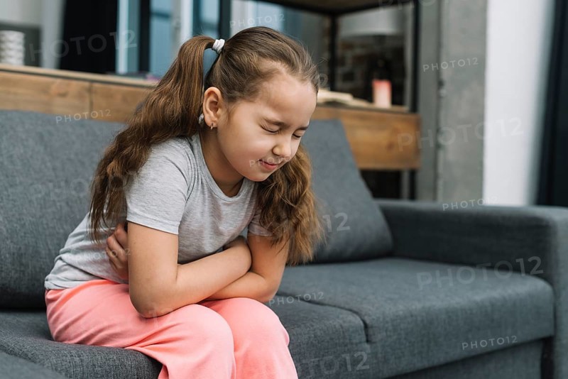 Little girl holding hands her stomach suffering from pain