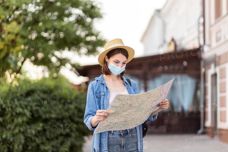 Traveller with hat medical mask checking map