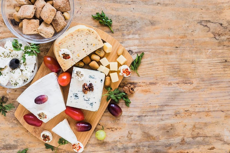 Cheese blocks with tomatoes parsley grapes wooden table