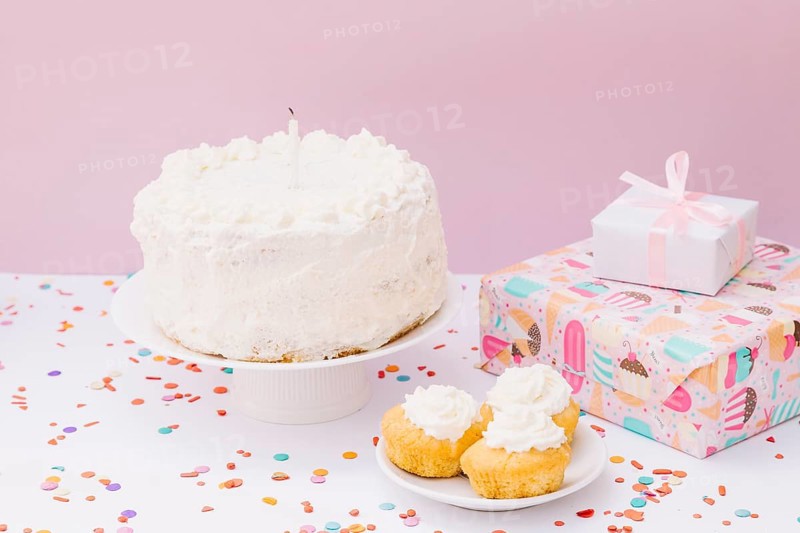 Birthday cake muffins gift boxes with confetti white desk against pink background