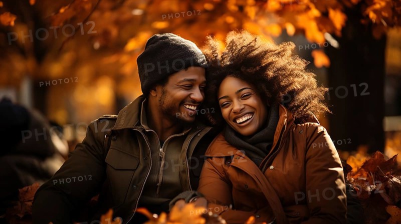 Happy warmly dressed young loving african american couple laugh as they enjoy the beautiful fall leaves in the park