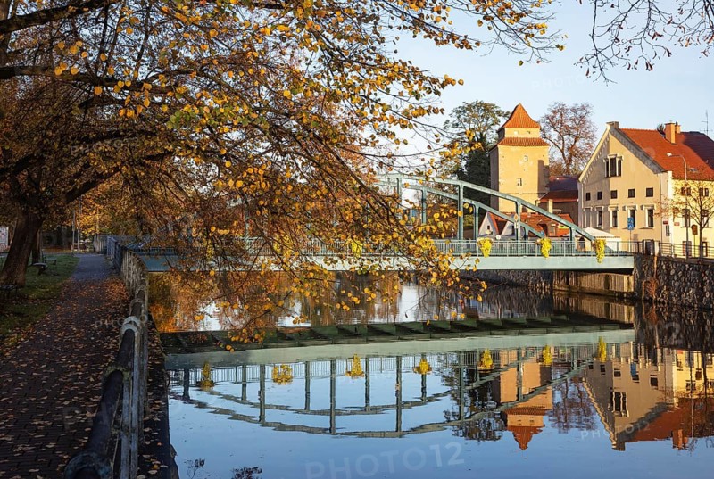Autumnal coloured trees with iron bridge over the river Maltsch with the city wall of the historical old town of Ceske Budejovice