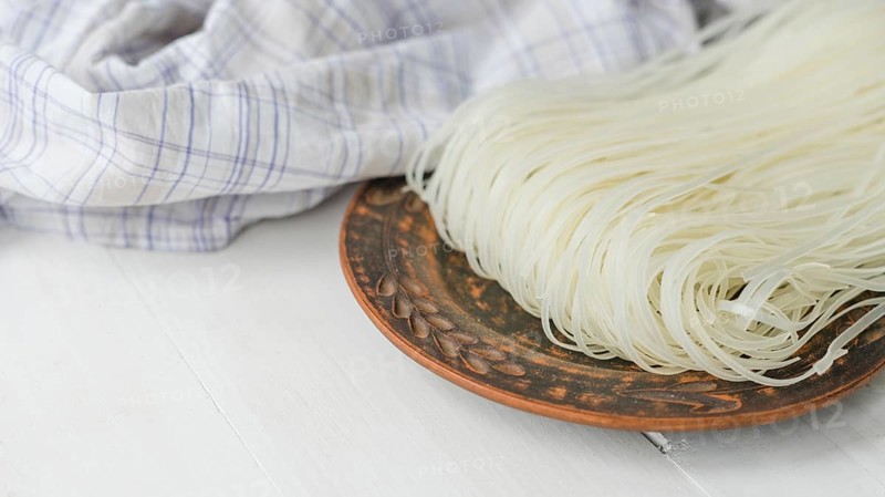 Dried rice vermicelli noodles circular plate near checkered cloth white surface