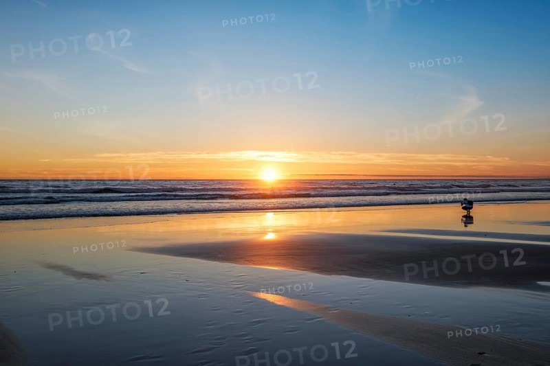 Atlantic ocean sunset with photographer silhouette taking images of surging waves at Fonte da Telha beach
