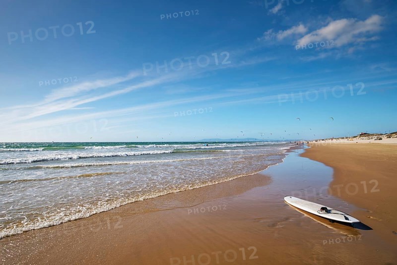 Sandy Atlantic ocean beach with surfboard at Fonte da Telha beach