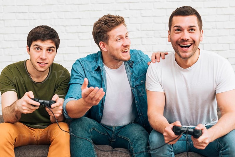 Three male friends sitting together enjoying video game