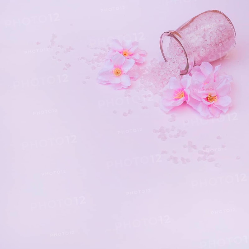 Artificial flowers spilled salt from jar pink background