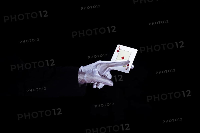 Magician holding aces playing card fingers against black background