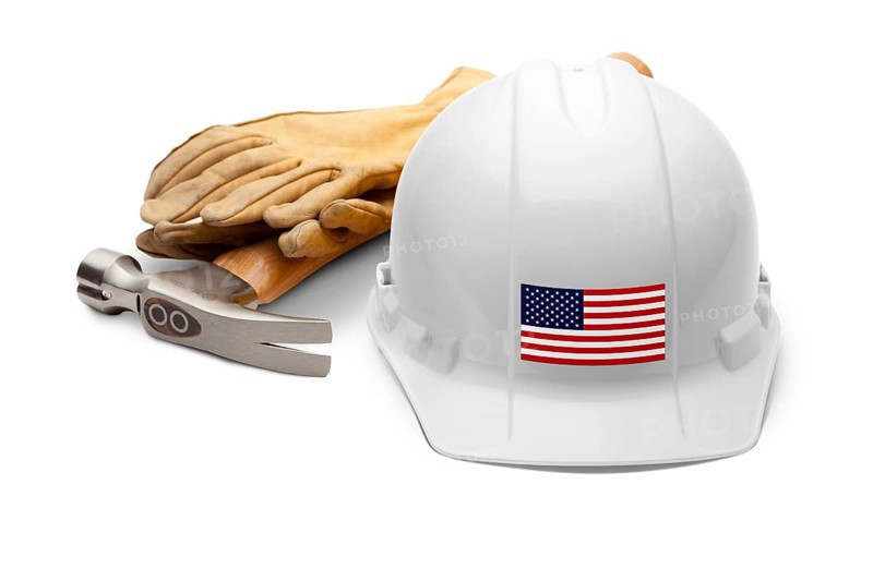 White hardhat with an american flag decal on the front with hammer and gloves isolated on white background