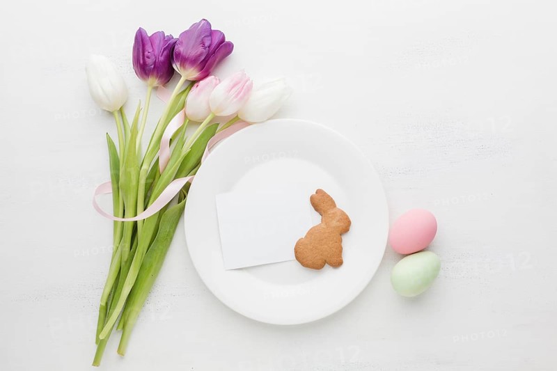 Flat lay bouquet tulips with plate colorful easter eggs