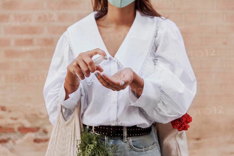 Front view woman with face mask using hand sanitizer