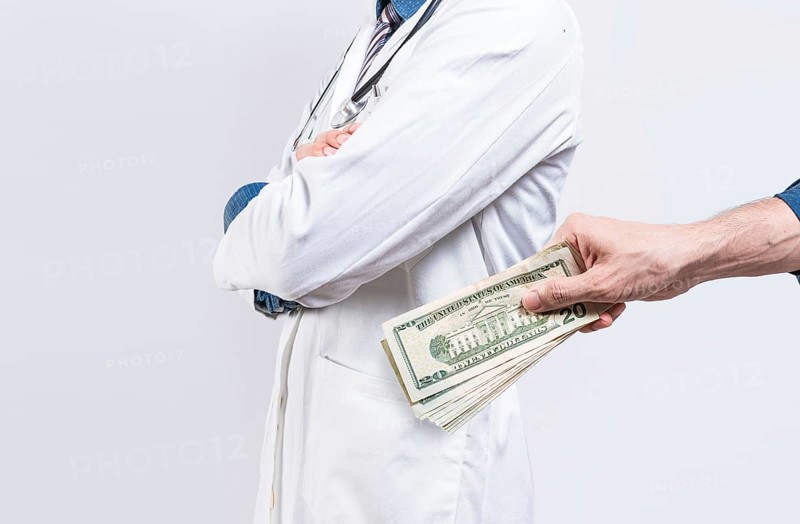 Hand of person bribing doctor. Hands putting money in doctor pocket