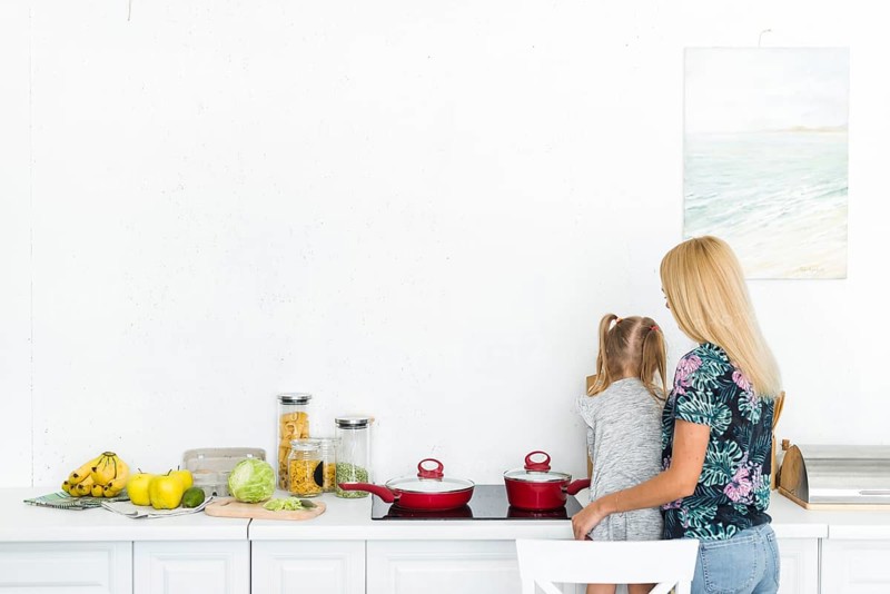 Rear view woman with her daughter kitchen