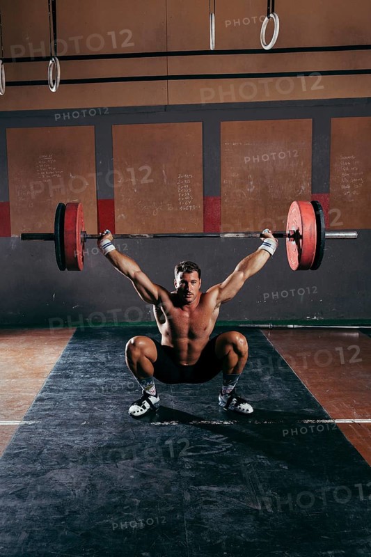 Gym concept with strong man lifting barbell