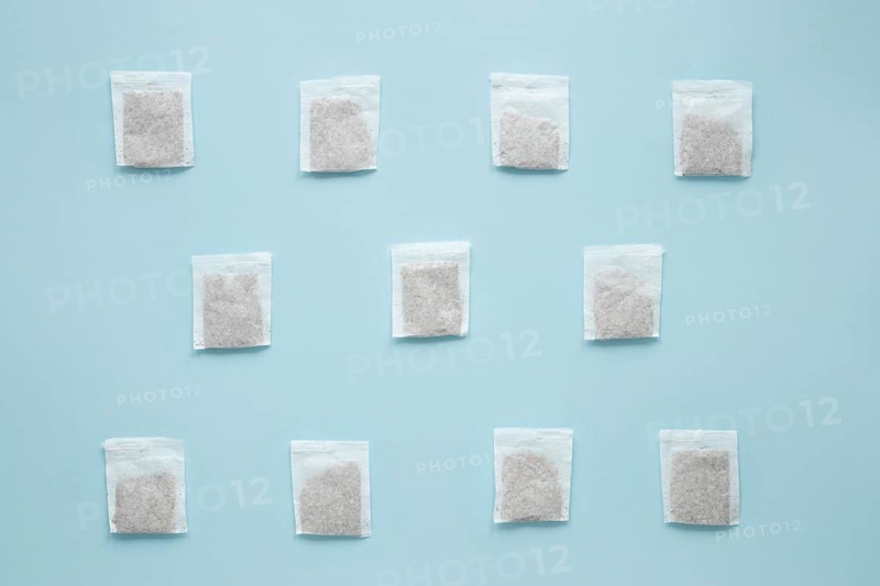 Overhead view teabags arranged against blue background