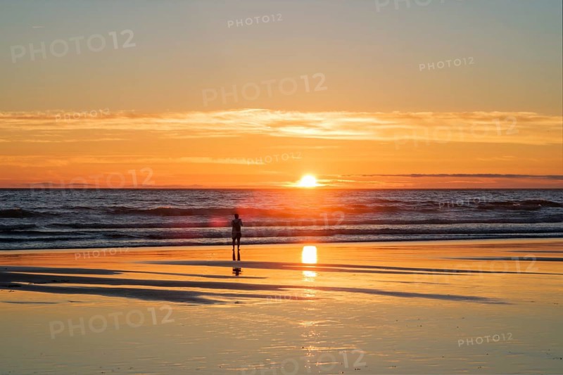 Atlantic ocean sunset with photographer silhouette taking images of surging waves at Fonte da Telha beach