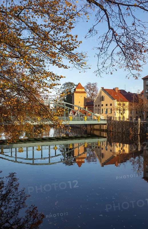 Autumnal coloured trees with iron bridge over the river Maltsch with the city wall of the historical old town of Ceske Budejovice