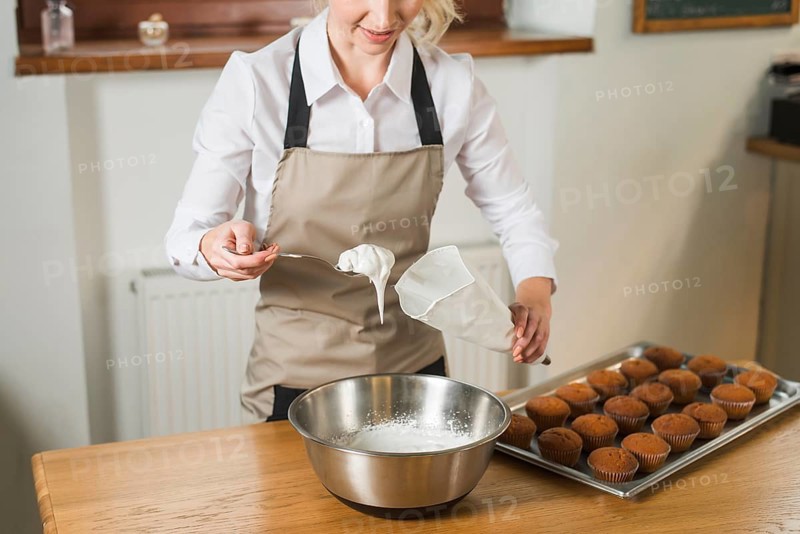 Close up young woman putting white cream pastry bag