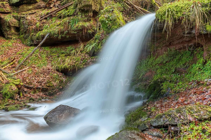 Beautiful fresh mountain waterfall in a wild and remote valley in winter. Vosges
