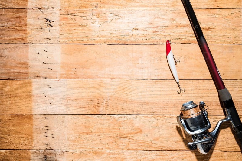 Fishing rod with red white fishing bait wooden plank