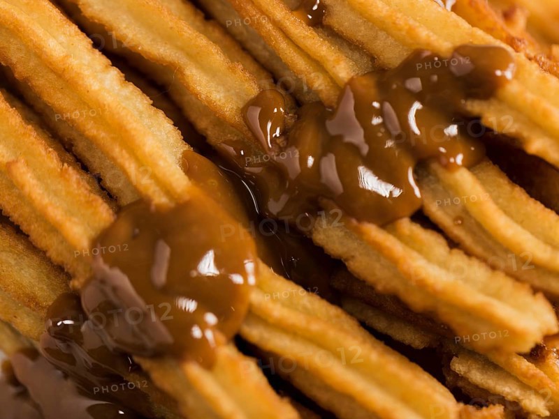 Close up fried churros with melted chocolate