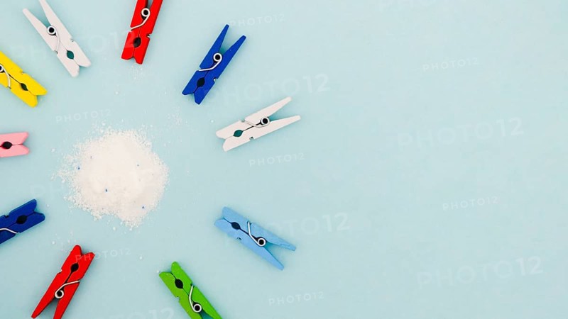 Flat lay colorful clothes pins surrounding detergent