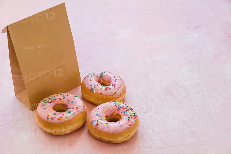 Three delicious donuts with parcel pink background