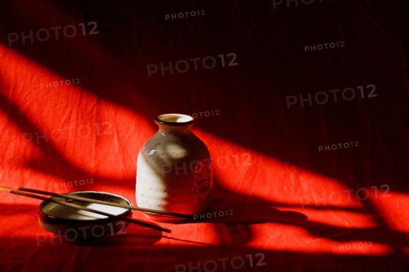 Light and shadows cast on incense sticks in a porcelain platter