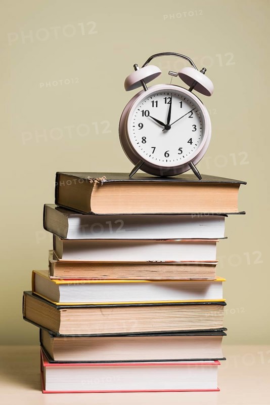 Alarm clock top stacked books wooden desk